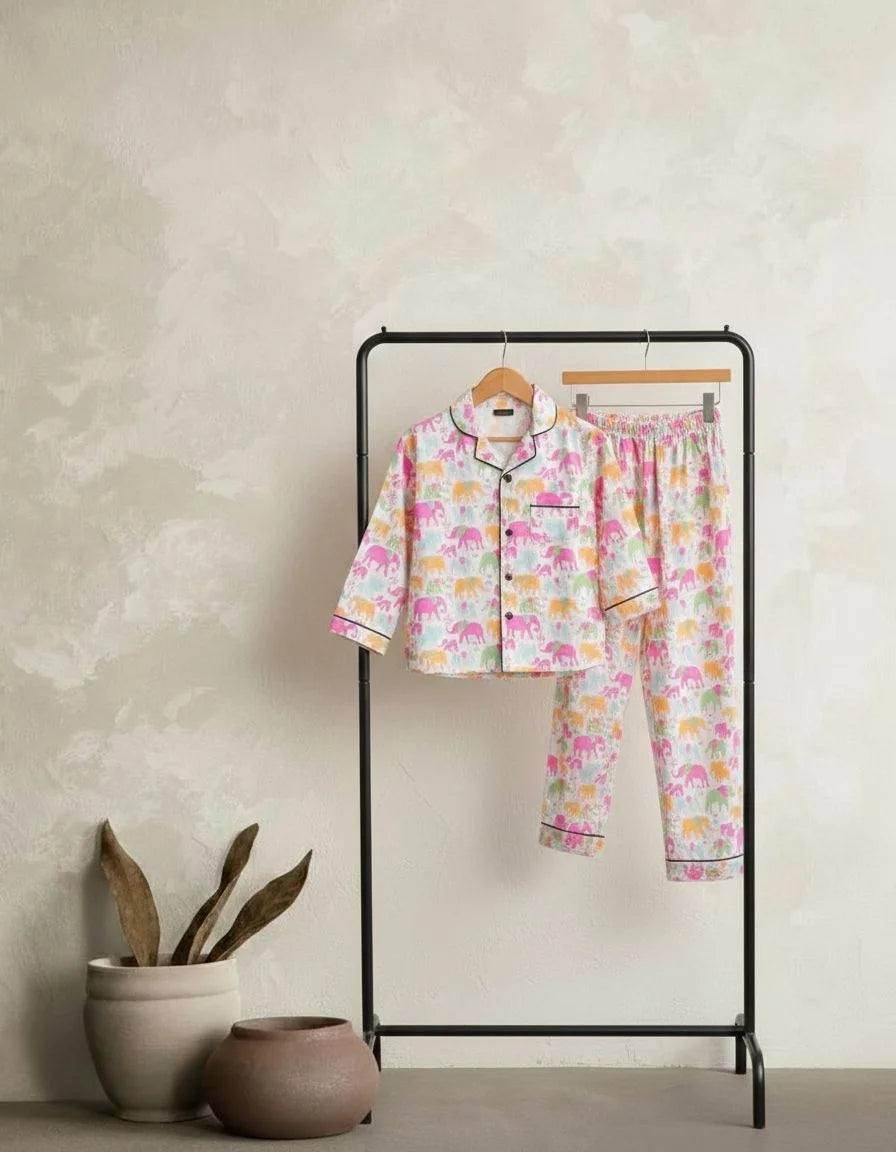 Children's pajama set with elephant pattern on a black rack against a beige wall.